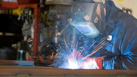 Welder with hood on creating sparks.