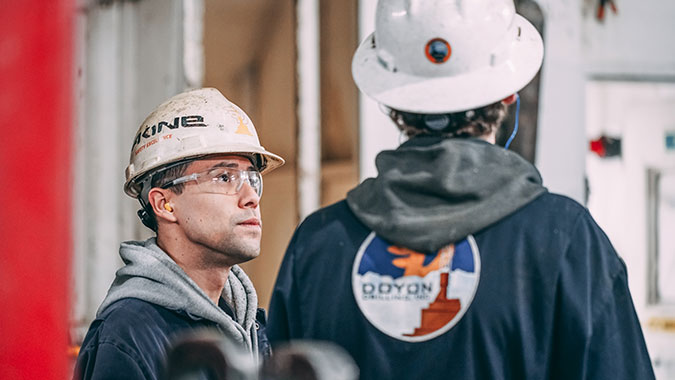 Two workers in hardhats confer on the job.